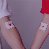 Two arms with bandages and heart stickers after blood donation