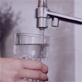 Hand filling a glass with water from a faucet