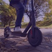 close up photo of person riding a scooter on a sidewalk