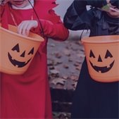 photo of two kids in costumes holding jack o lantern candy buckets