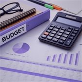 Calculator, budget binder, and financial charts on a desk.