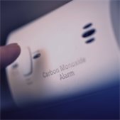 Finger pressing the test button on a carbon monoxide alarm