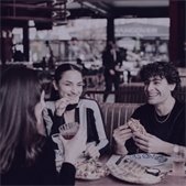 Three people smiling and enjoying food together at a restaurant.
