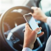 person driving behind the wheel with phone in hand. 