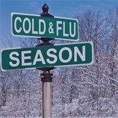 Street signs reading “Cold & Flu Season” in a snowy setting