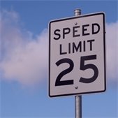 photo of road speed limit sign showing speed limit of 25 miles per hour with blue sky and white clouds in background
