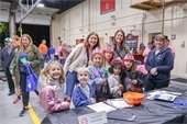 group of girl scouts wearing pink plastic firefighter helmets smiling for photo