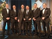 Six men pose together holding an award at the ACEC event