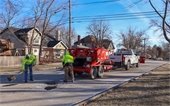 photo of public works crew working to patch a pothole on a residential street