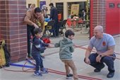 two young boys pulling on rope with firefighter watching nearby