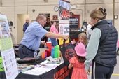 photo of firefighter handing out bags at table to two young children