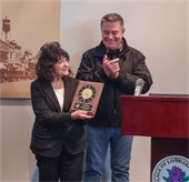 Carol Bauer holding a commemorative clock plaque during her recognition ceremony