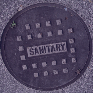 photo of sewer manhole top with word imprinted in the metal