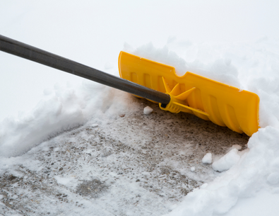 yellow shovel pushing snow on sidewalk