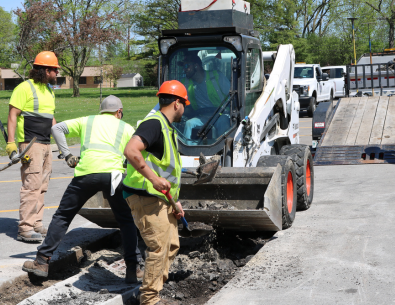 photo of three public works members working on road with bright yellow vests