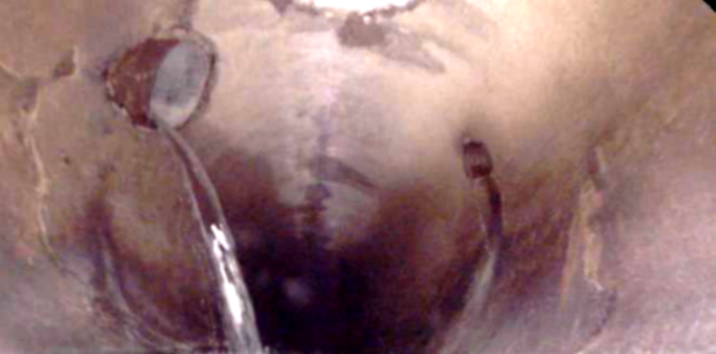 Interior of a large sewer pipe showing water leaking from two small openings.